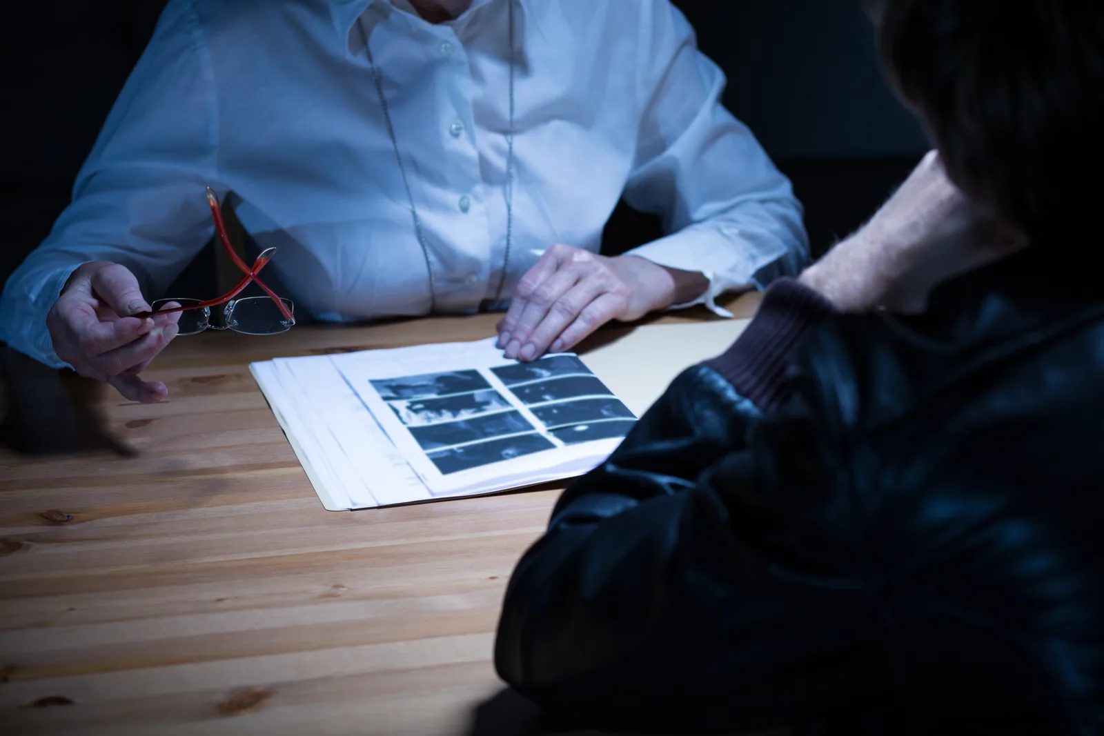 Pedestrian accident attorney reviewing crosswalk photos and a police report with an injured client at a law office conference table