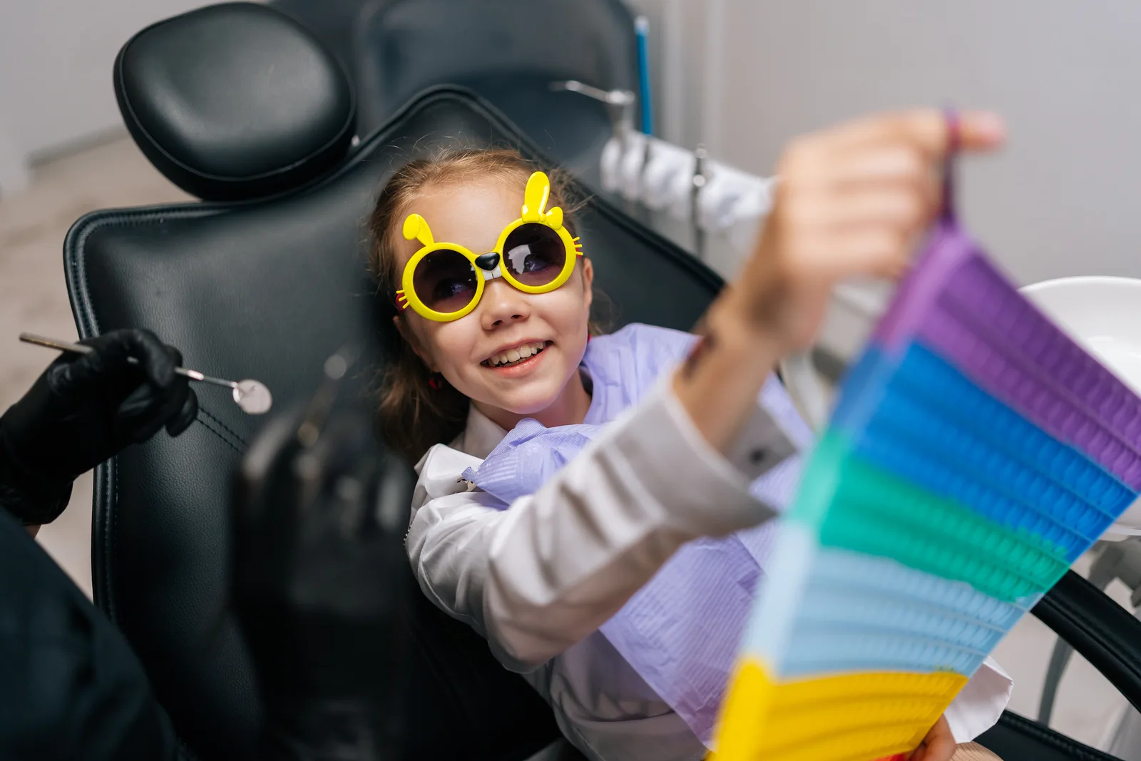 Pediatric dentist smiling with a young child in the exam chair during a gentle checkup in a bright, kid-friendly dental office