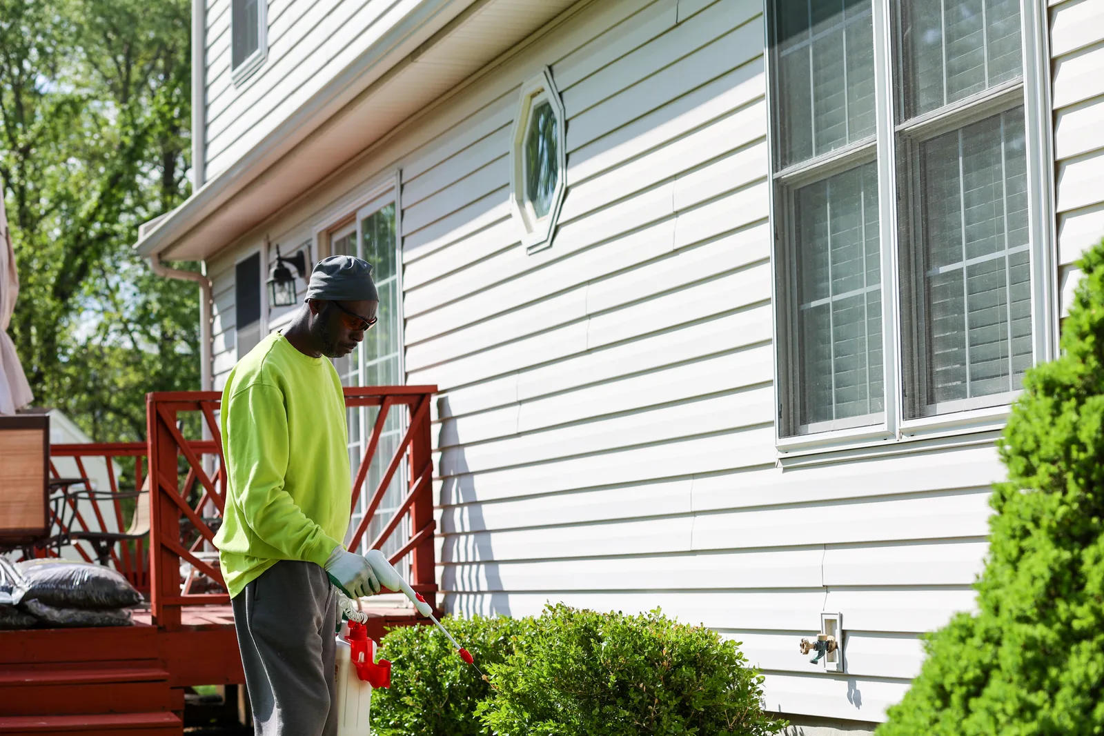 Pest control technician spraying a barrier treatment along the foundation of a customer's home
