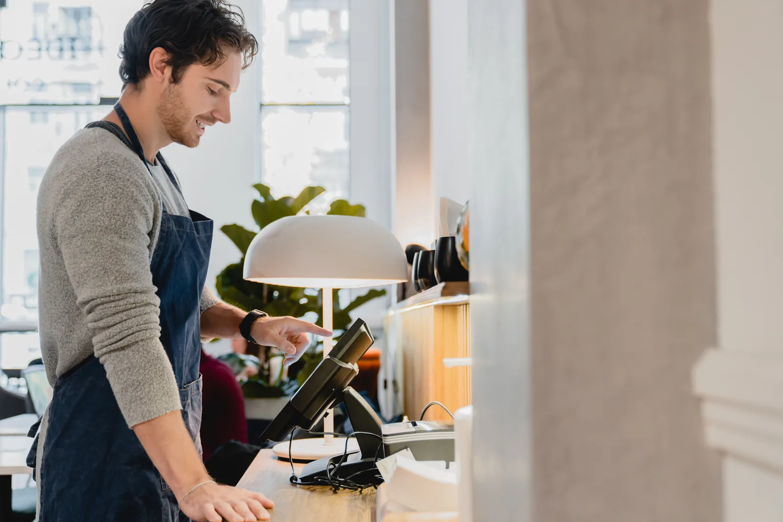 POS installer setting up a countertop terminal and card reader at a restaurant checkout counter