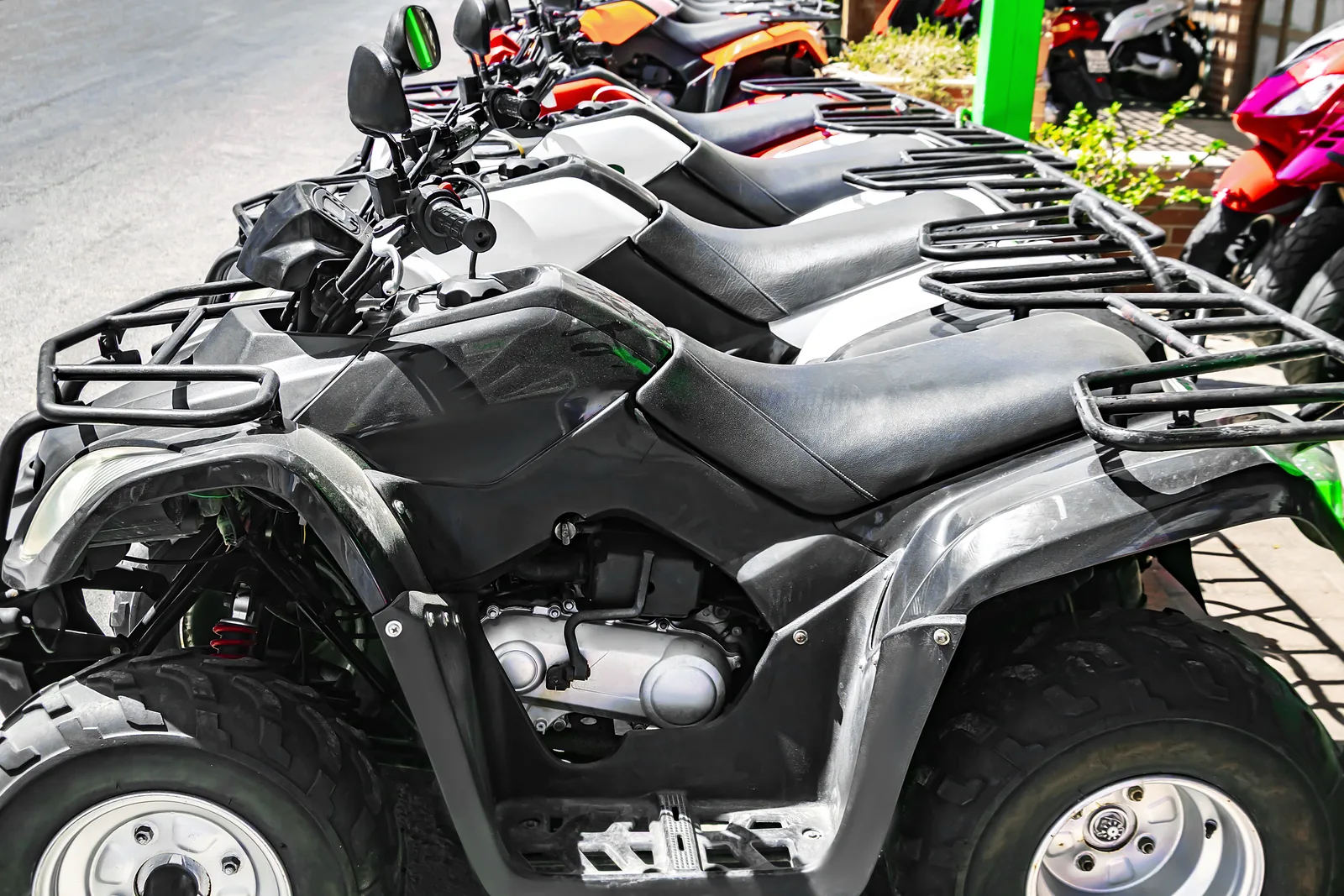 Salesperson walking a customer through a lineup of ATVs and UTVs on a powersports dealership showroom floor