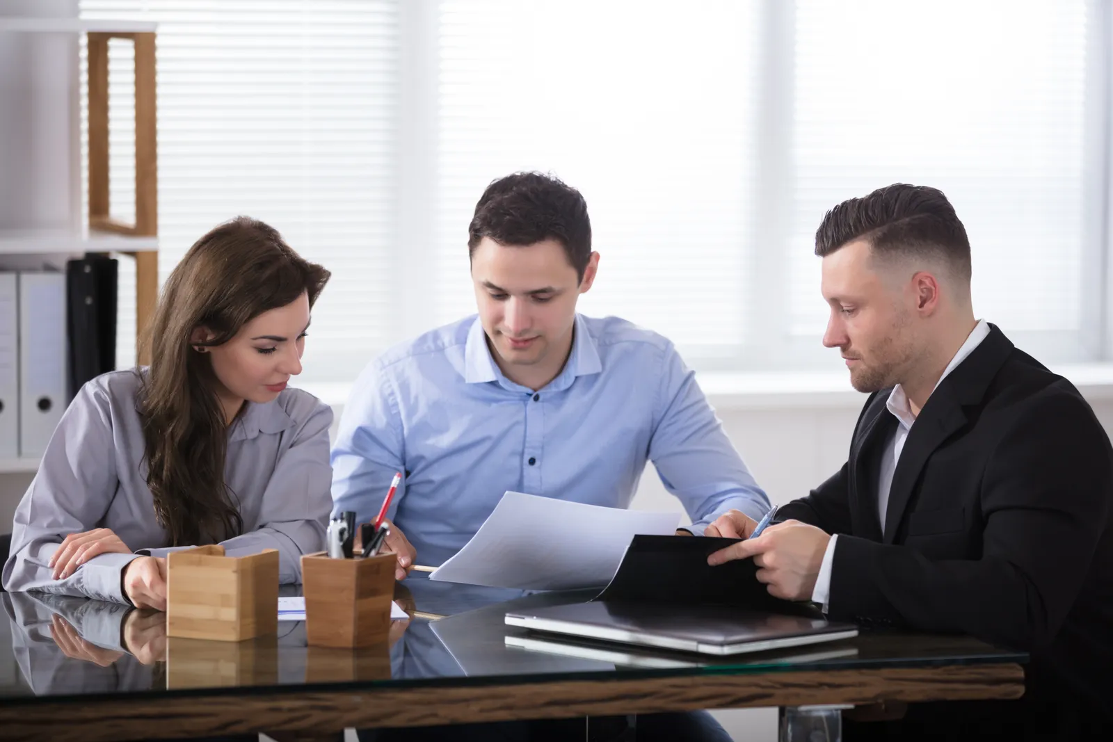 Prenuptial agreement attorney reviewing a draft agreement with an engaged couple at her office desk