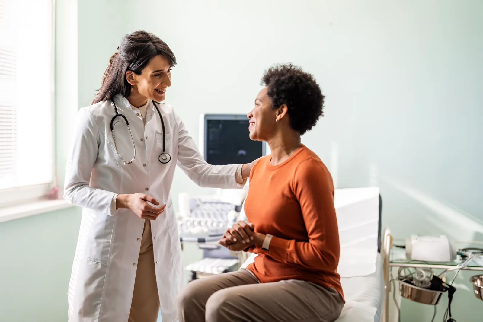 Family doctor talking with a patient during a primary care checkup in an exam room