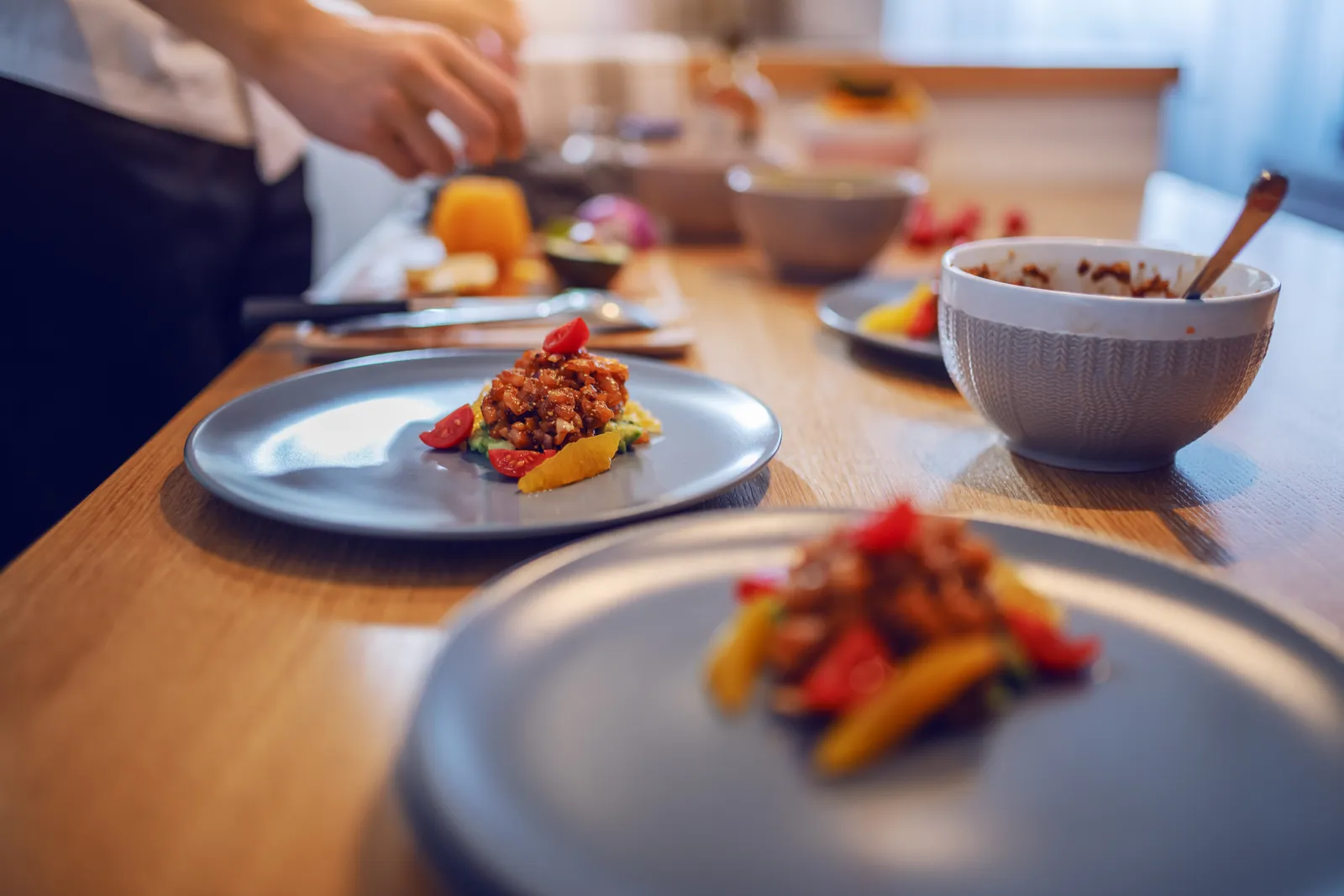 Private chef plating a multi-course dinner on a client's kitchen island during an in-home dining experience