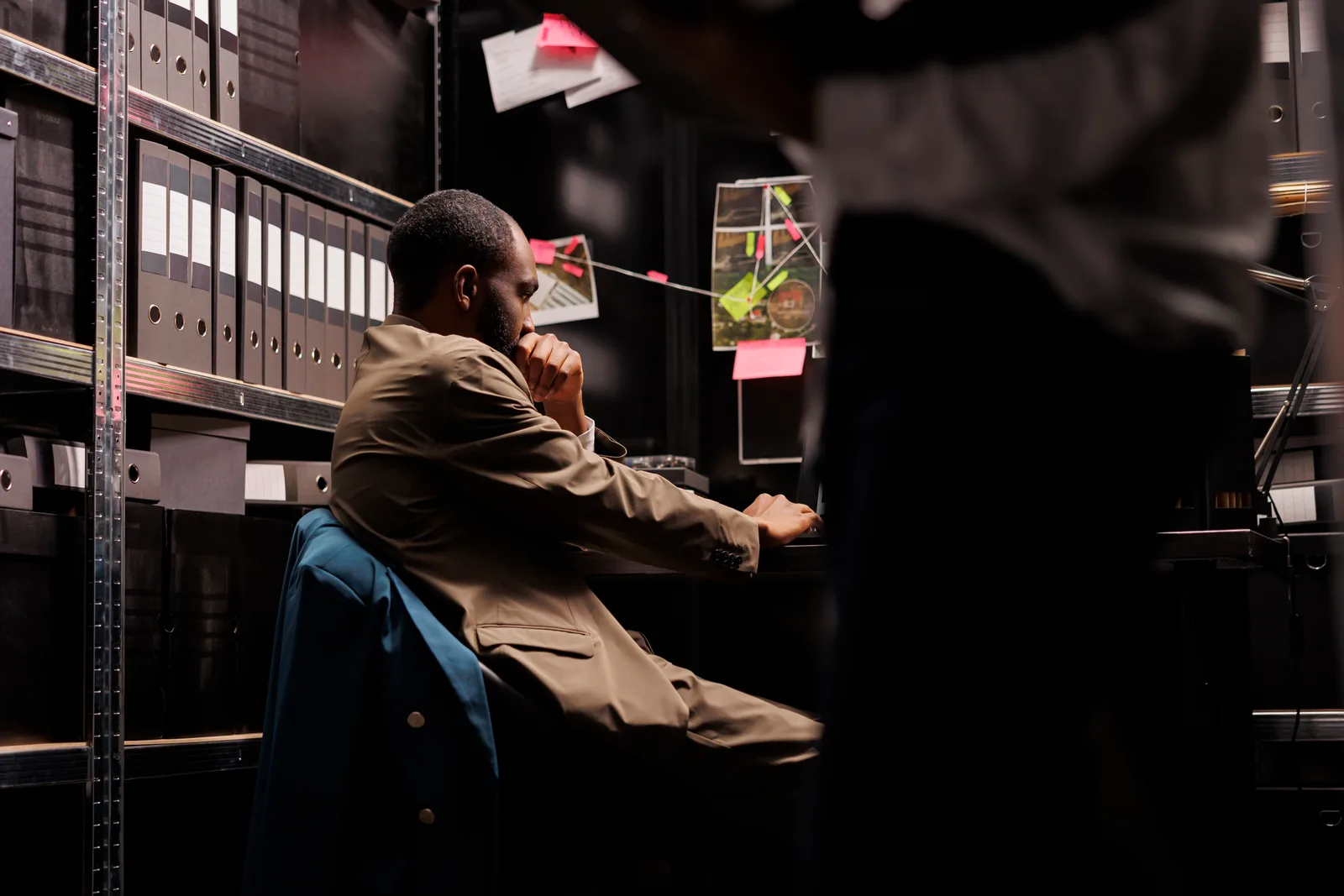 Private investigator reviewing surveillance photos and case files at his desk