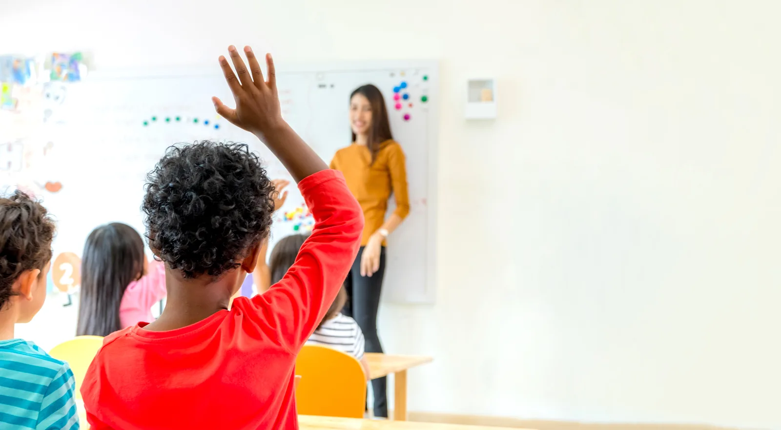 Teacher leading a small class discussion with students in a bright private school classroom