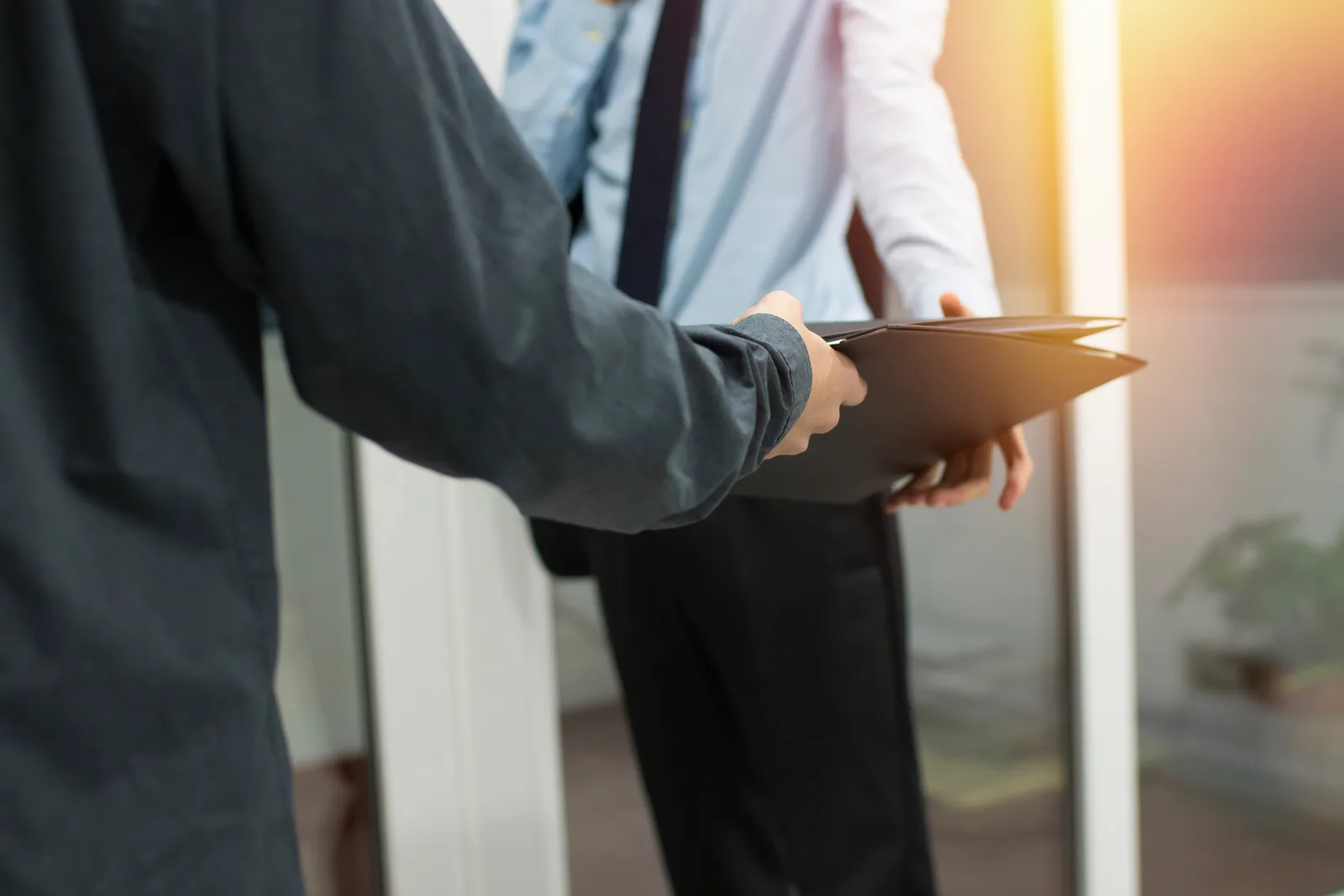Process server in a suit handing a legal document to a man at his front door