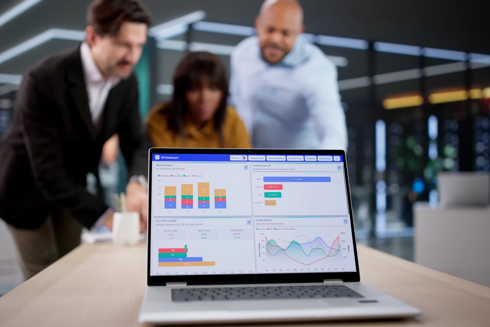 Product team reviewing a user funnel and retention dashboard together at a laptop in their office