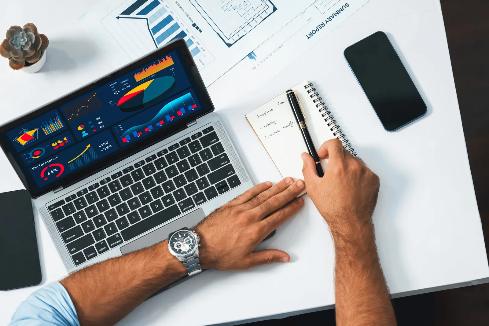 Productivity app founder reviewing habit-streak and signup analytics on a laptop, with a notebook and daily planner on the desk