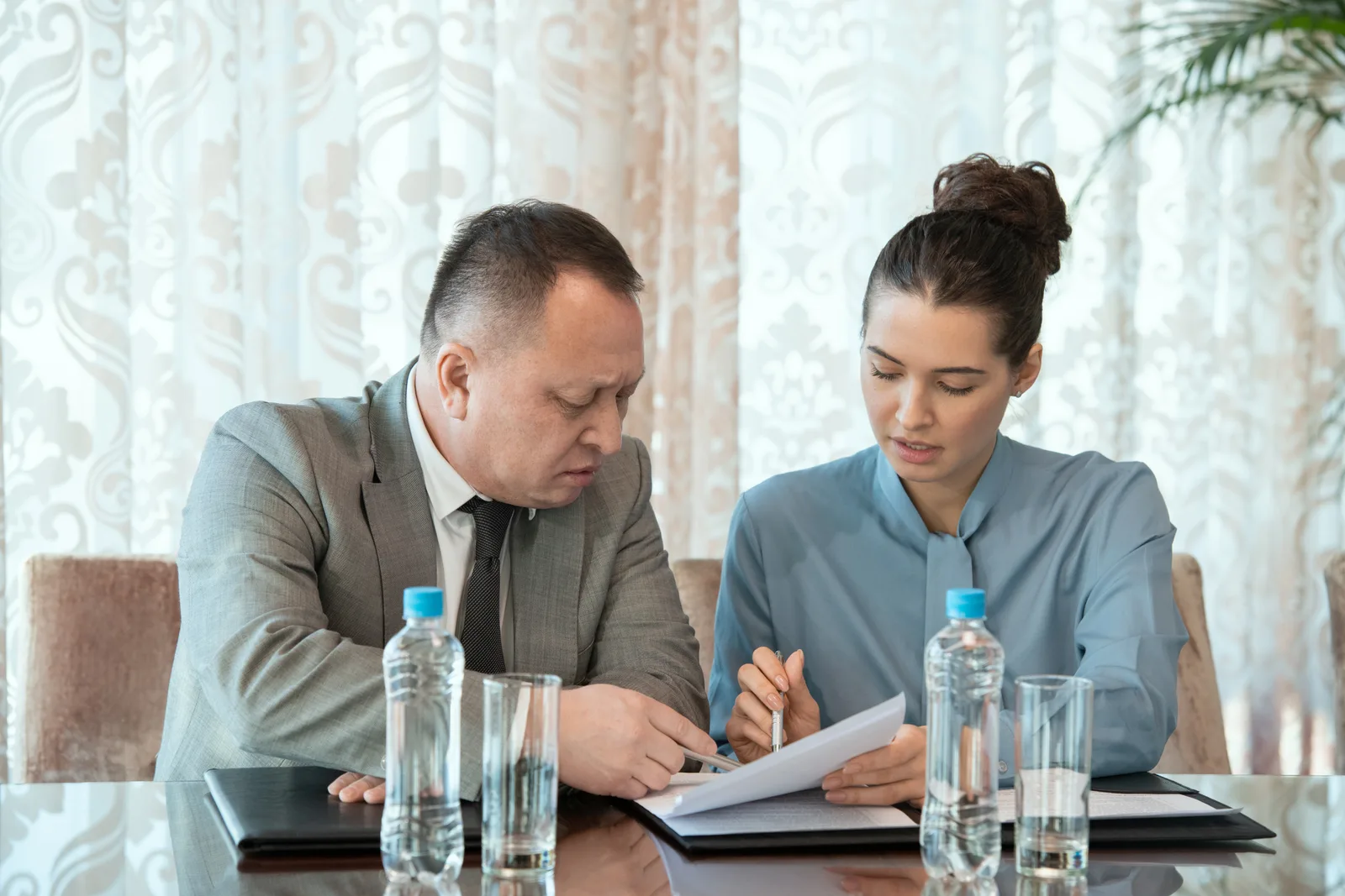 License defense attorney reviewing a state licensing board complaint letter with a nurse client at a conference table