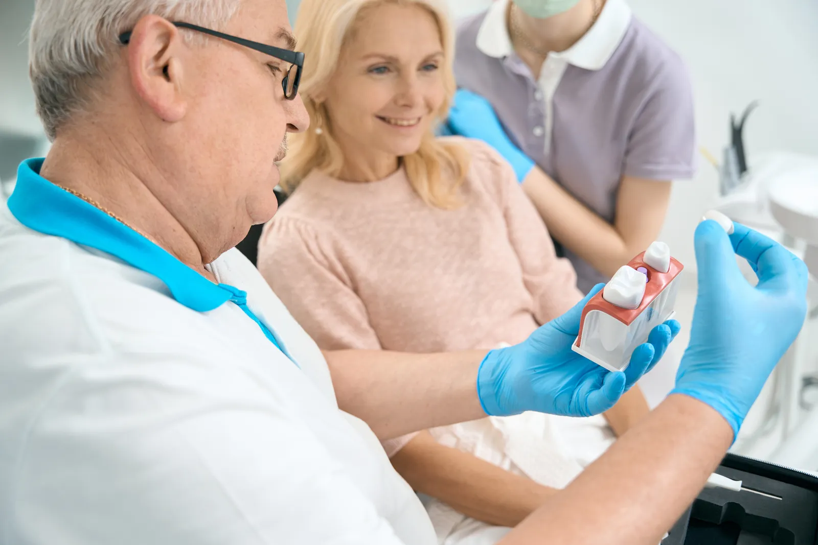 Prosthodontist showing a patient a full denture model during a restorative consultation in a treatment room