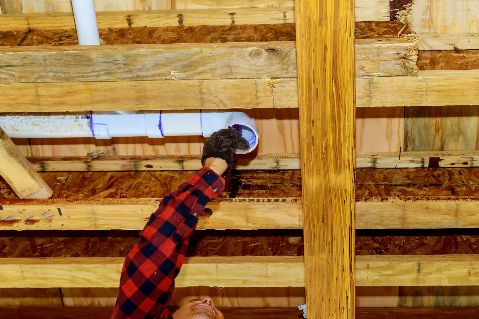 Radon mitigation technician installing a vent pipe system along a basement wall