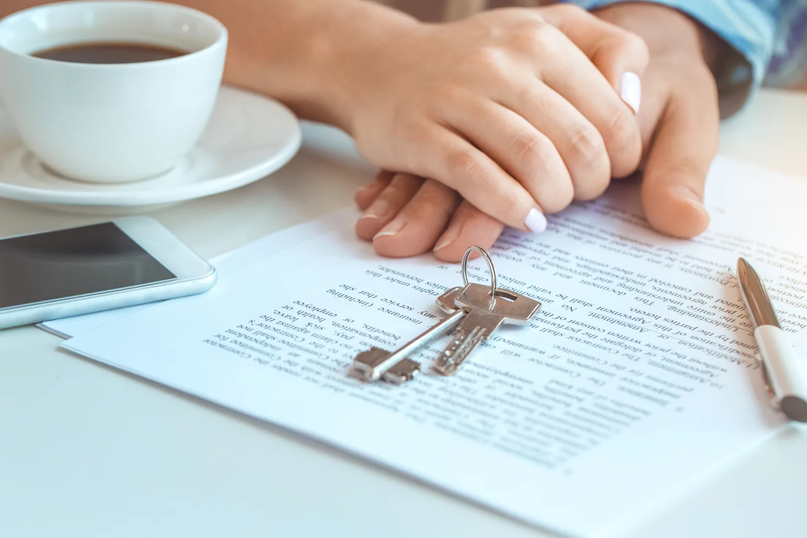 Real estate lawyer reviewing closing documents with a young couple buying a home, house keys and paperwork on the office desk