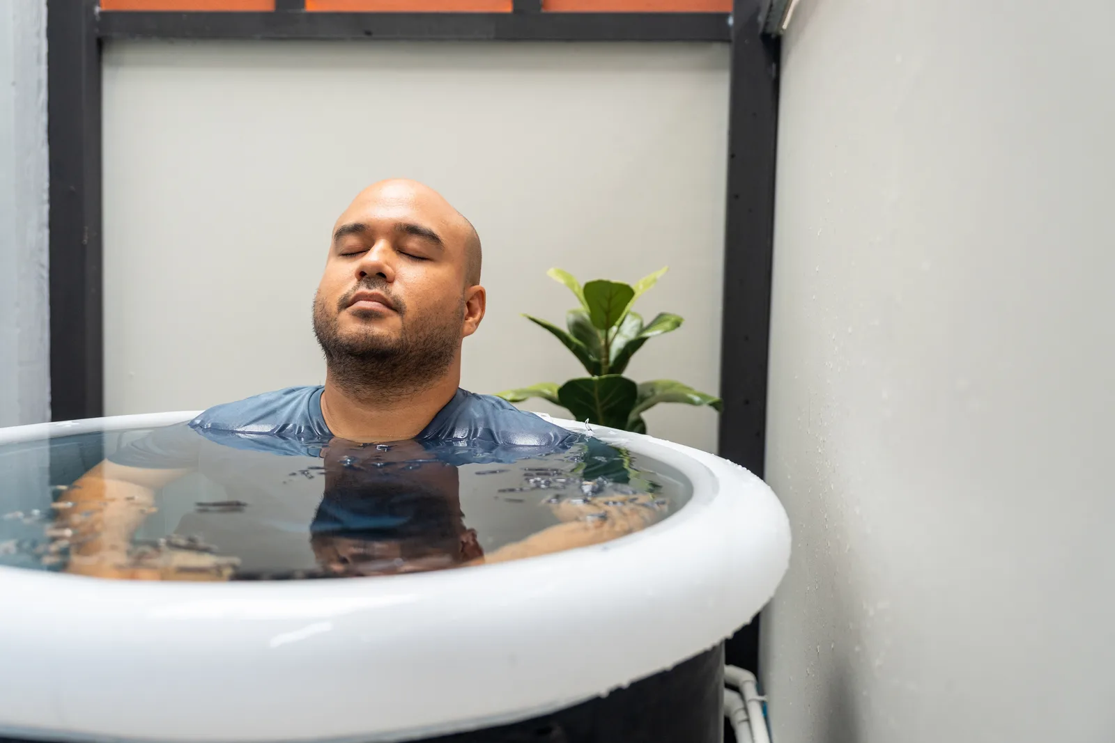 Client submerged in a cold plunge tub at a recovery and wellness studio