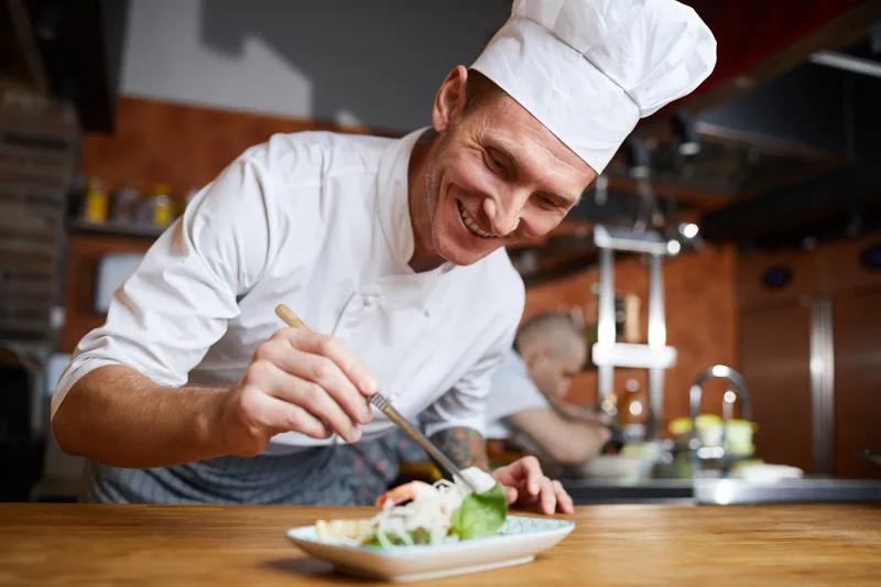 Chef plating a gourmet dish in a busy restaurant kitchen