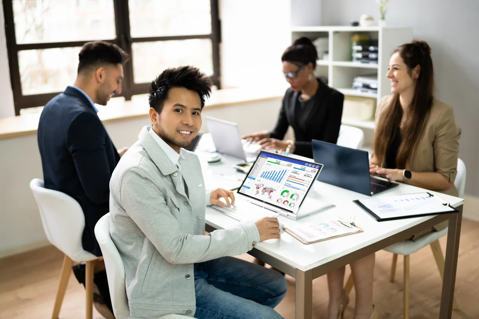 Revenue cycle management software team reviewing a claims-denial and days-in-AR dashboard together at a laptop in their office