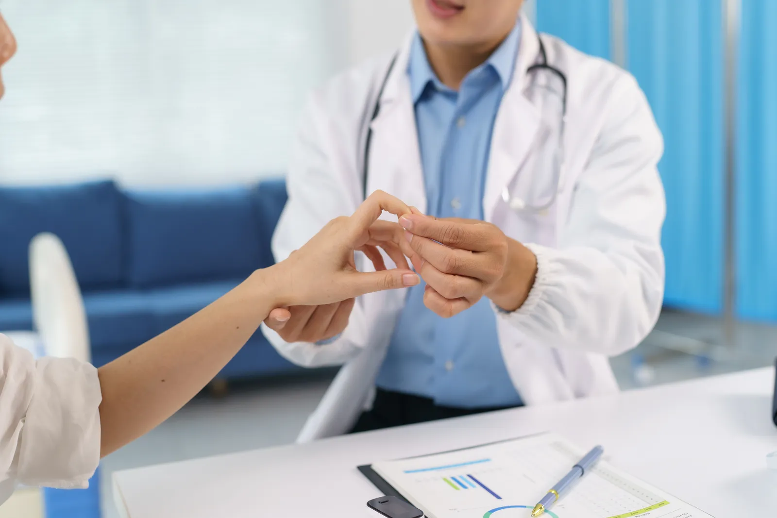 Rheumatologist gently examining a patient's hand and finger joints for swelling during an office visit