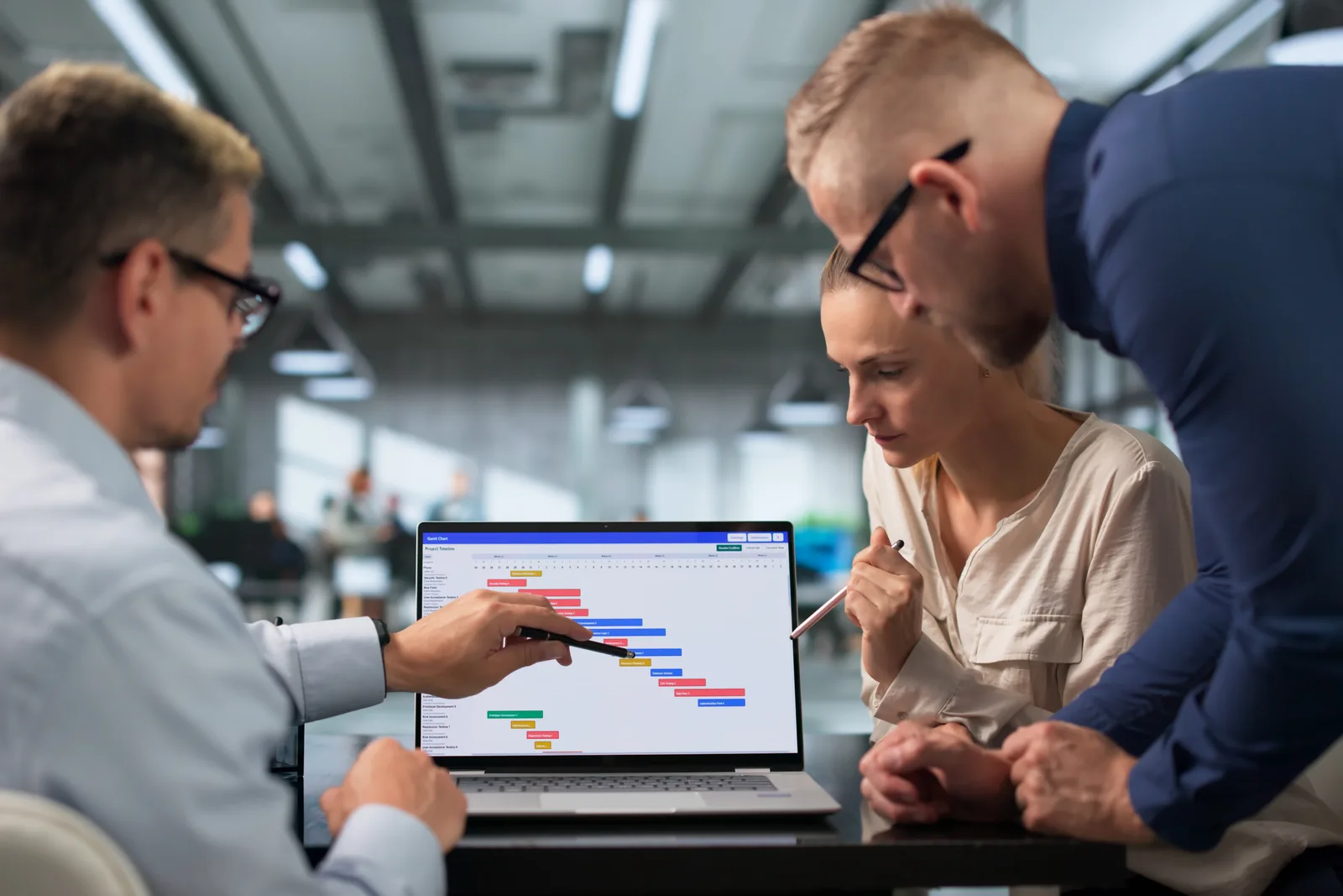 Software team reviewing a roofing job's aerial measurement report and production schedule together at a laptop in their office