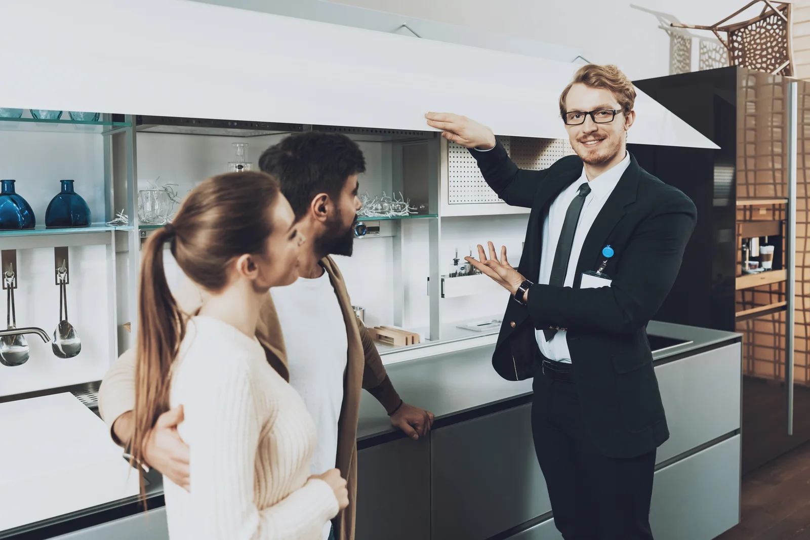 Salesperson walking a couple through a travel trailer's interior on an RV dealership lot
