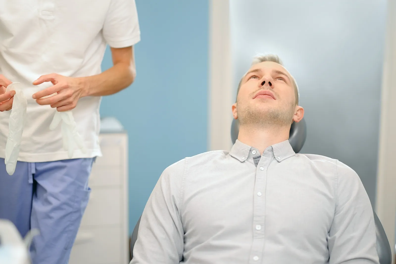 Dentist checking on a relaxed patient receiving nitrous oxide sedation during a dental procedure