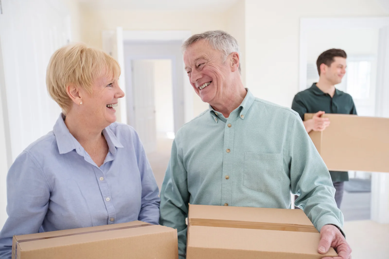 A senior move manager helping an older woman sort keepsakes and pack moving boxes at her kitchen table