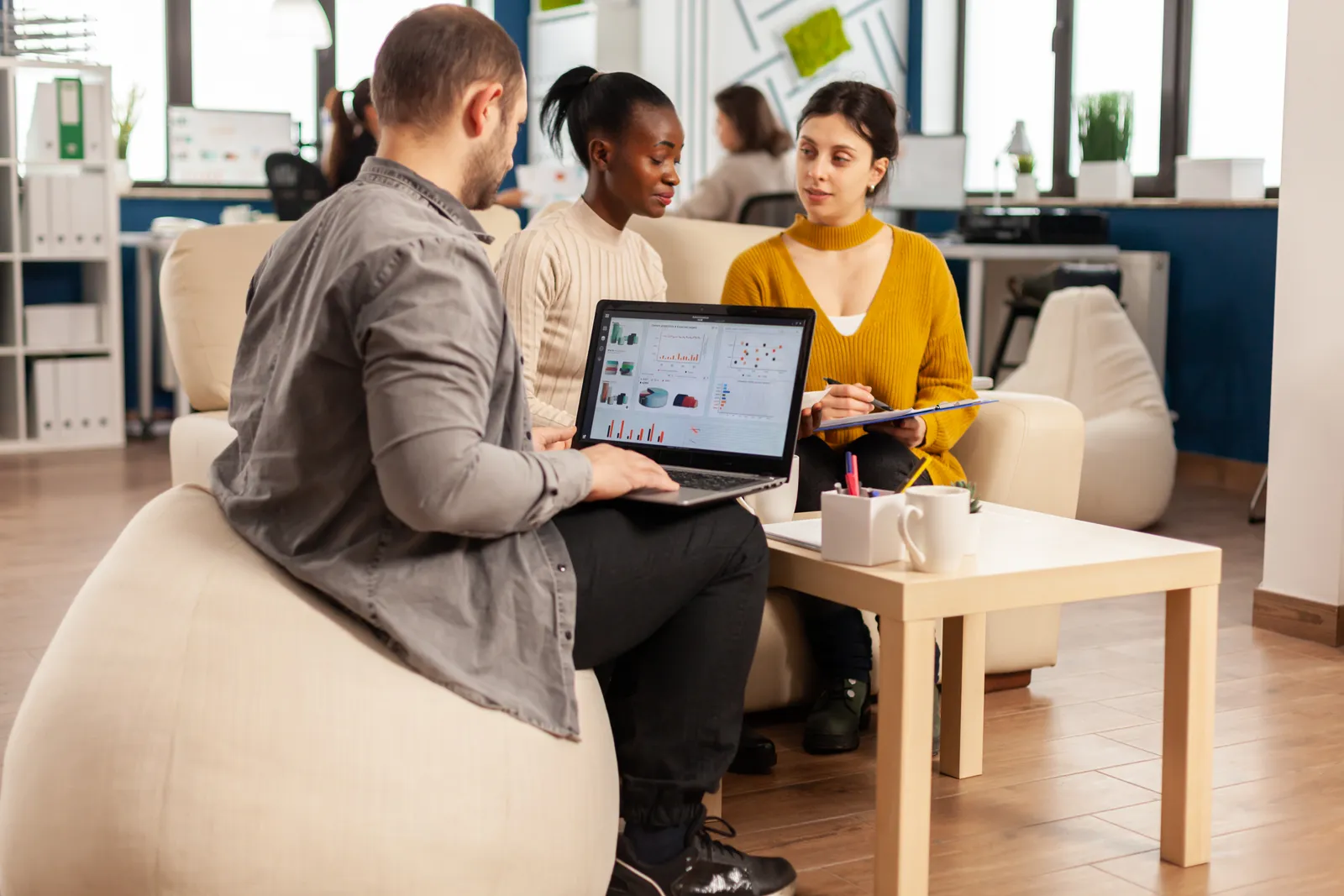 Slack app development team reviewing install and workspace-activation metrics together at a laptop in their office