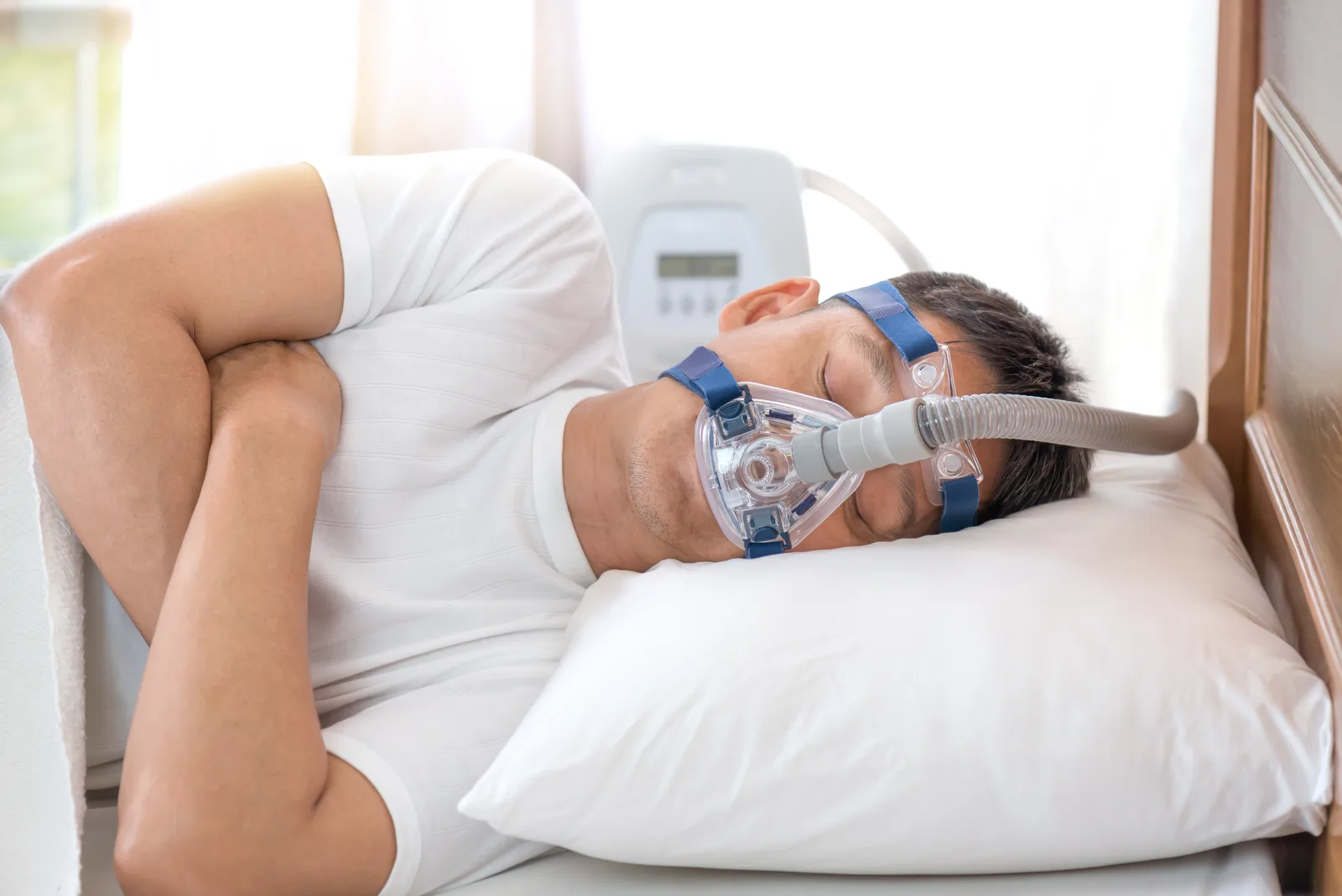 Patient asleep at home in their own bed, wearing the CPAP mask their sleep clinic fitted for nightly apnea therapy