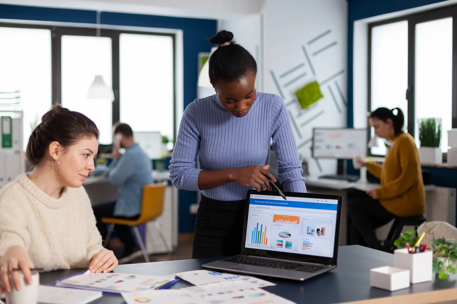 Small-business software team reviewing signup and churn dashboards together on a laptop in their office