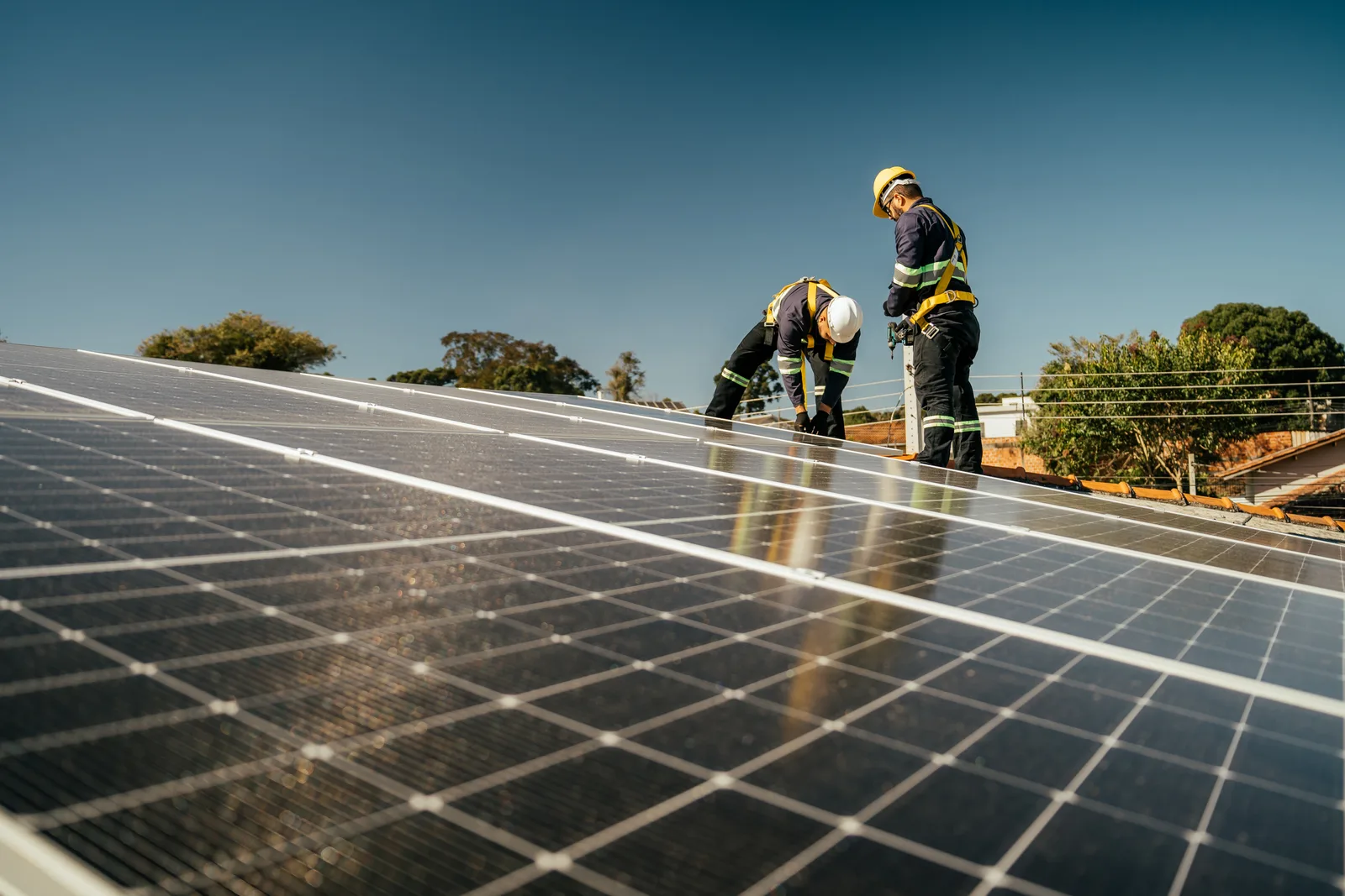 Installation crew bolting solar panels to the pitched roof of a suburban family home
