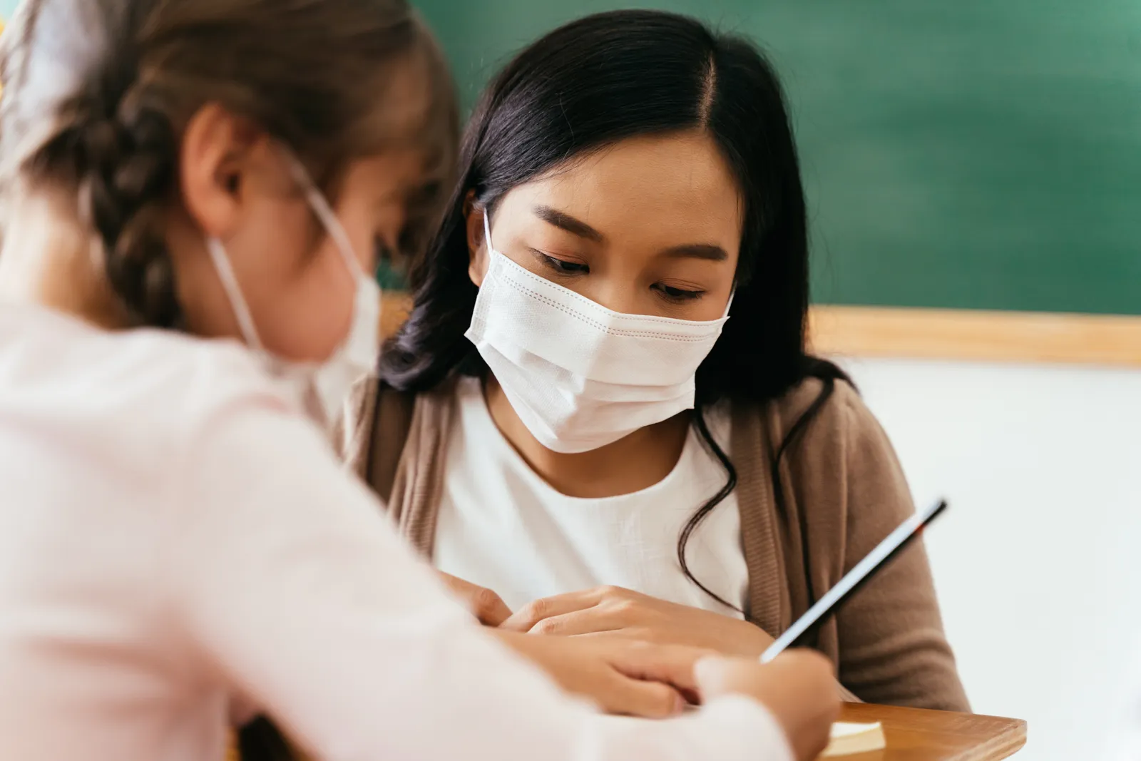 Teacher working one-on-one with a young student in a classroom