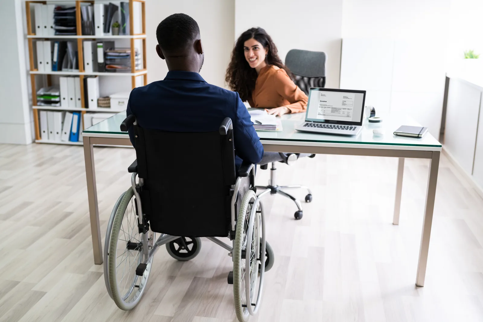 Spinal cord injury attorney reviewing a life-care plan with a client who uses a wheelchair in a law office conference room