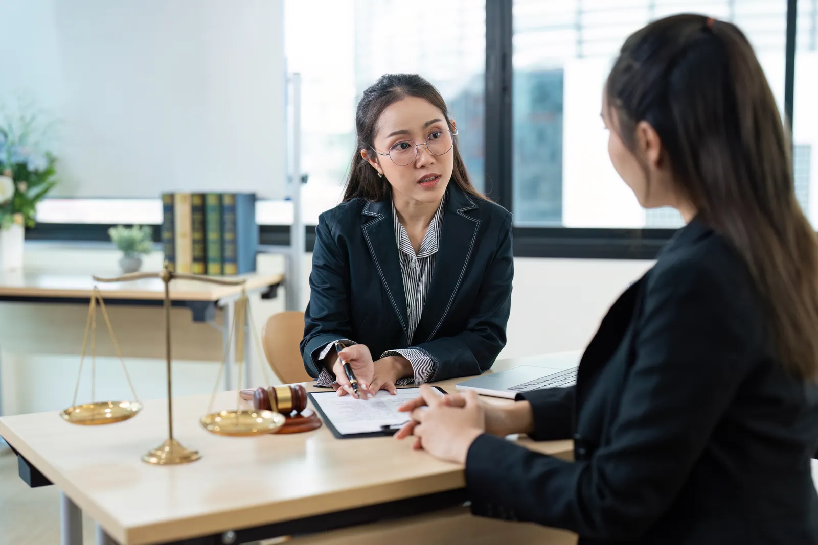 Sports lawyer reviewing a contract with a client at her office desk