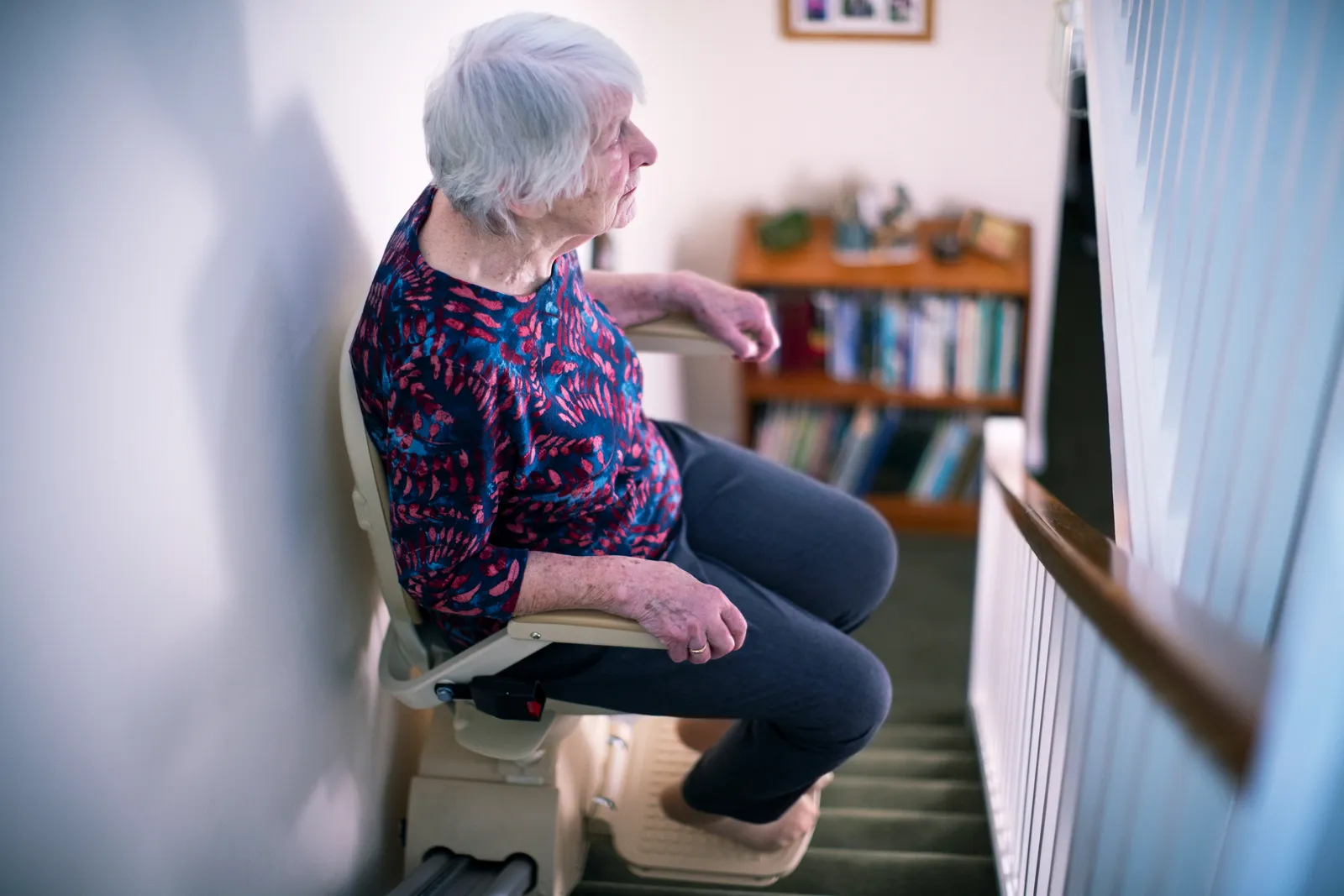 Senior woman riding a stairlift down her home staircase