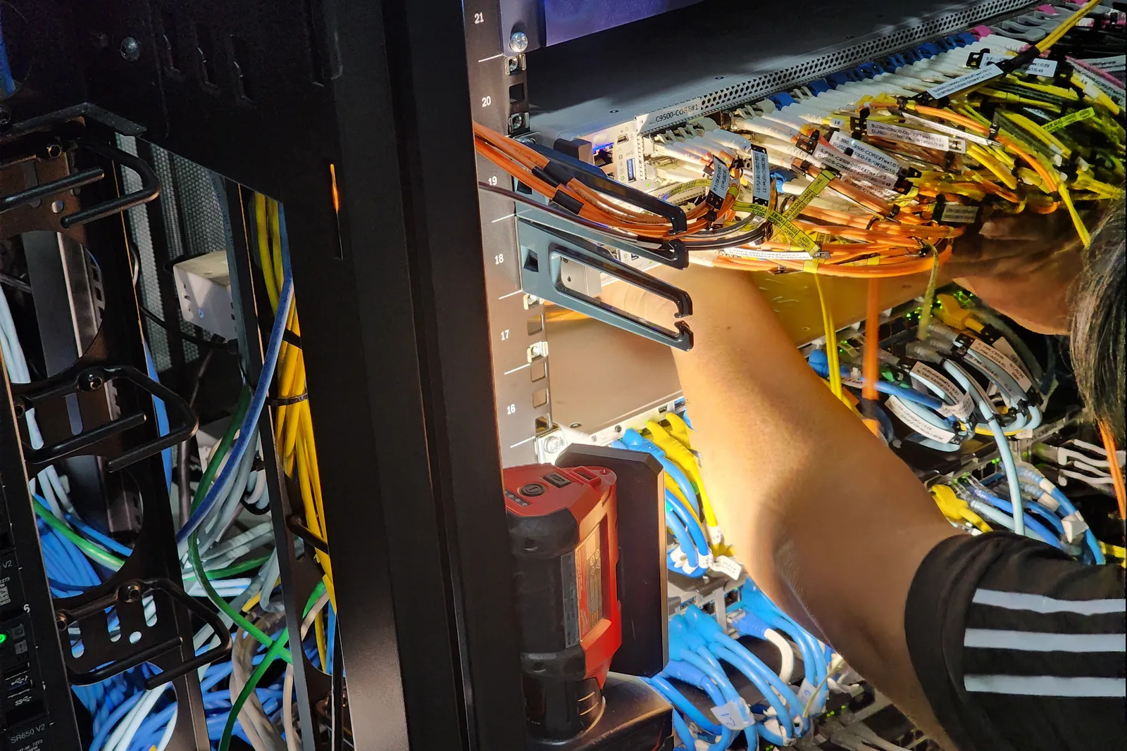Technician installing and labeling structured cabling in a data rack inside a commercial server room