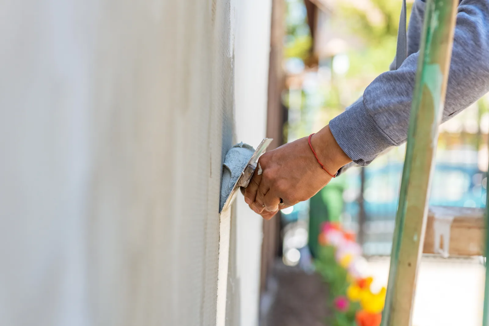 Stucco contractor troweling a fresh textured finish coat onto an exterior wall