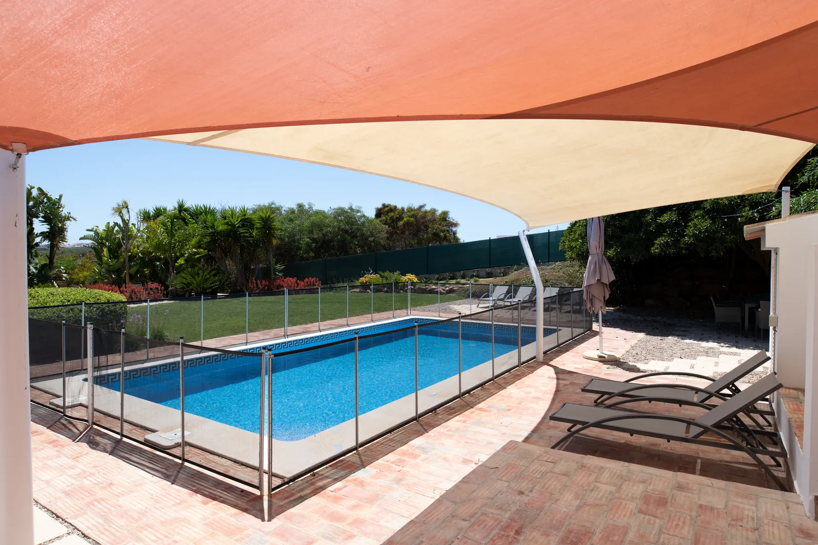 Backyard swimming pool enclosed by a mesh safety fence
