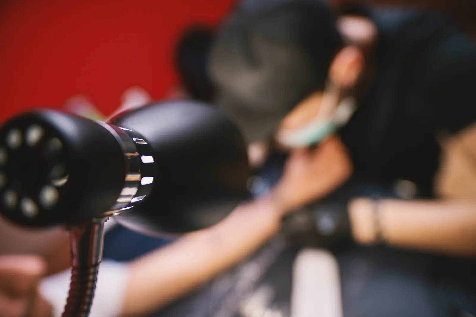 Tattoo artist in black gloves working on a client's forearm piece at a well-lit studio station