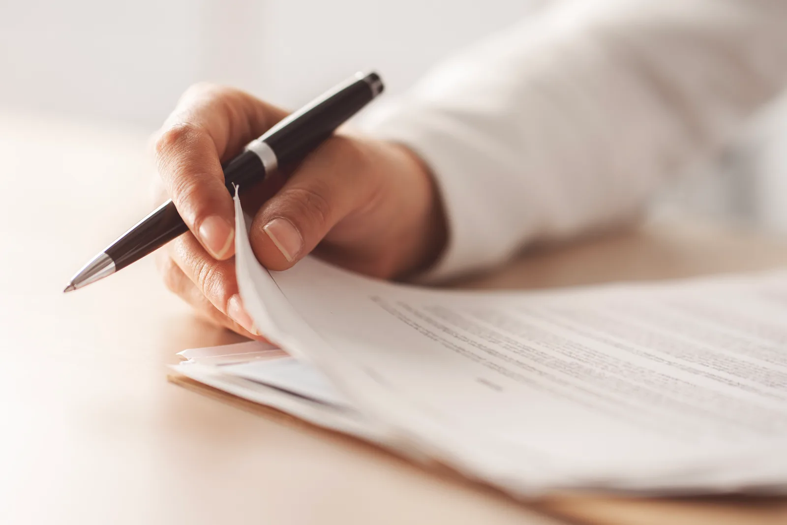 Close-up of a hand reviewing and signing tax documents at a desk