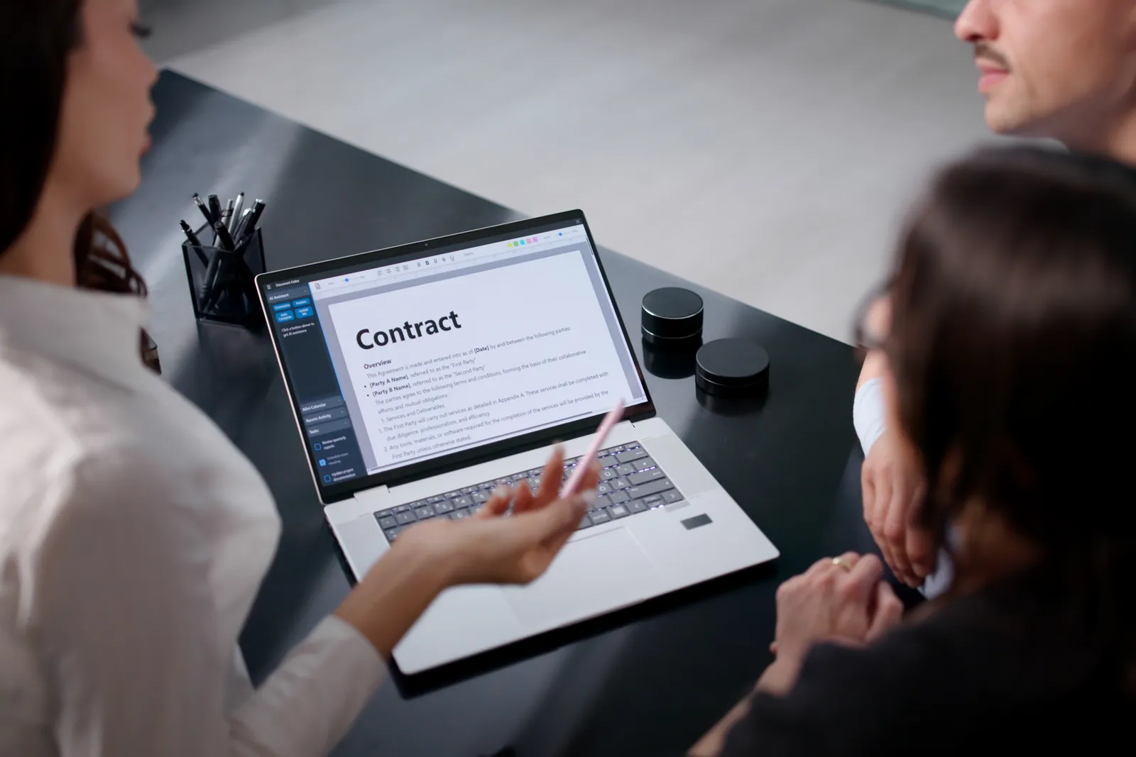 Technology transactions lawyer reviewing a SaaS agreement with a software company client at a laptop in a modern office