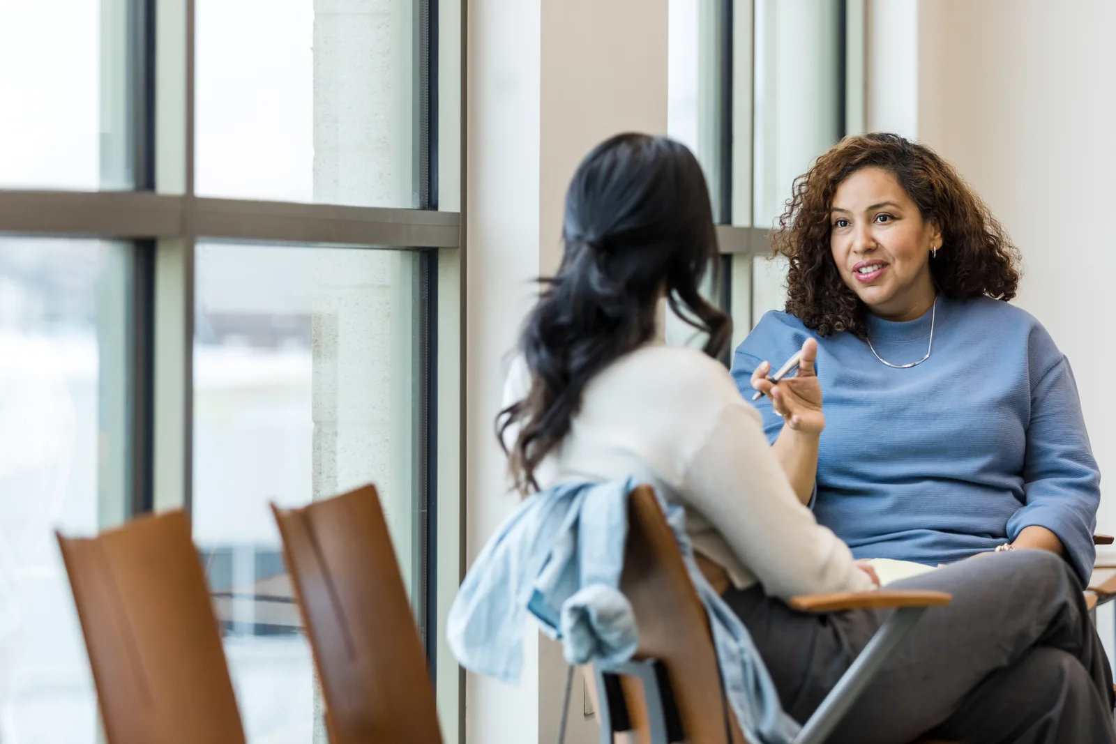 Therapist listening to a client during a session in a calm, sunlit counseling office