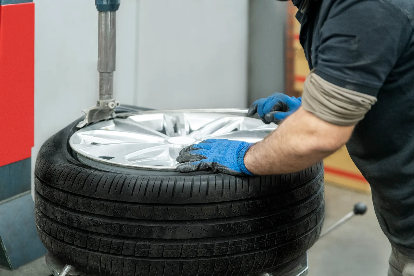 Tire technician tightening lug nuts on a freshly mounted tire in a shop service bay