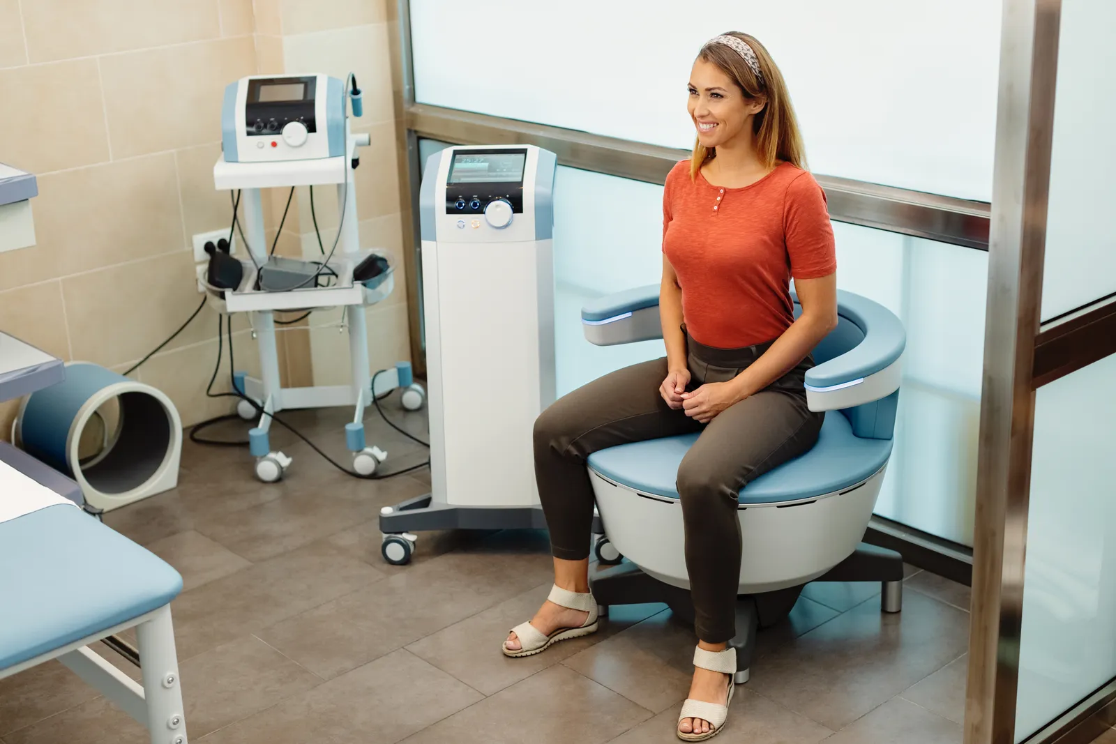 Patient seated in a treatment chair beside TMS equipment in a clinic room