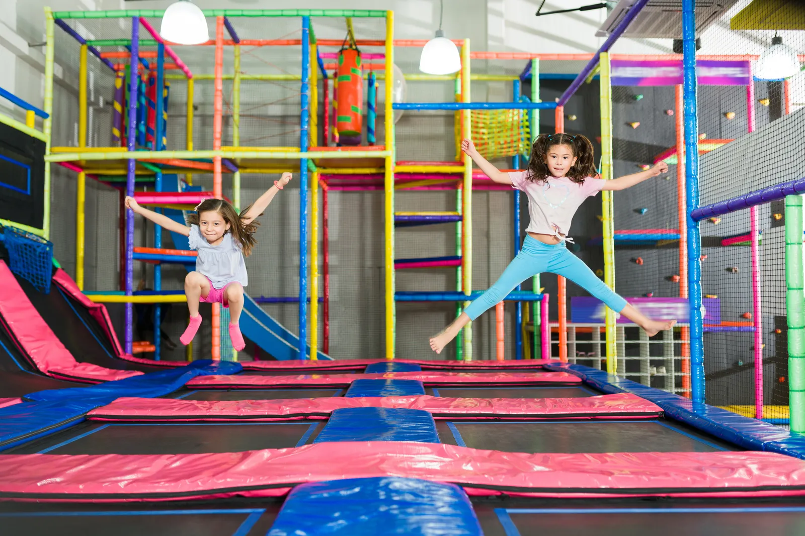 Kids jumping across a row of connected trampolines at an indoor trampoline park during open jump