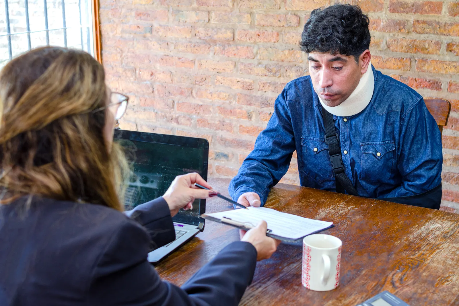 Truck accident lawyer reviewing 18-wheeler crash photos and black box data with an injured client at a law office conference table