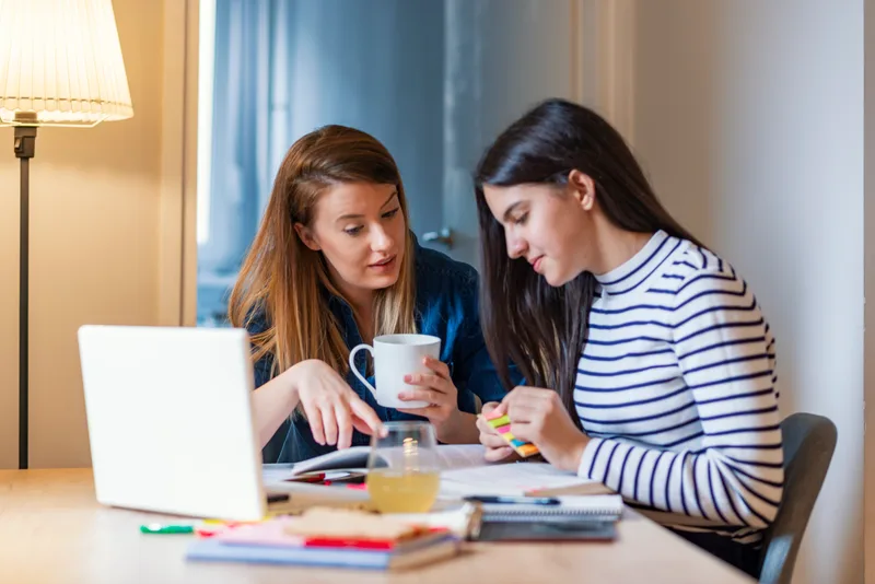 Tutor helping a student with schoolwork at a table