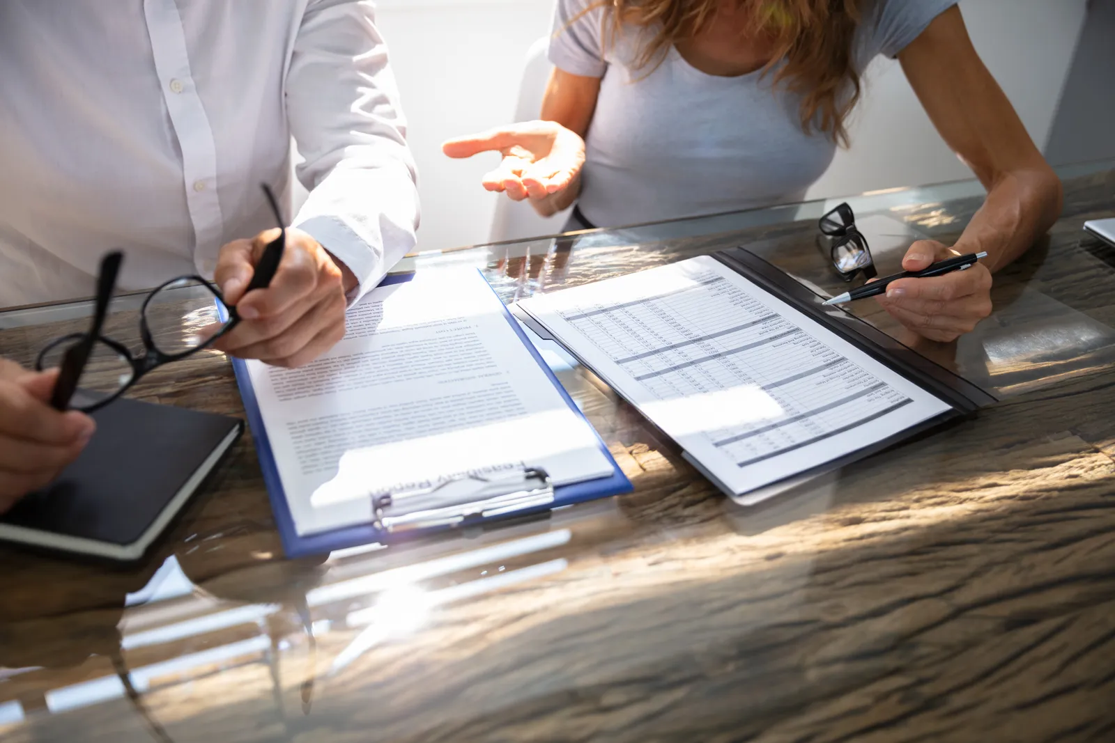 Auto insurance claim form on a clipboard beside reading glasses on a desk