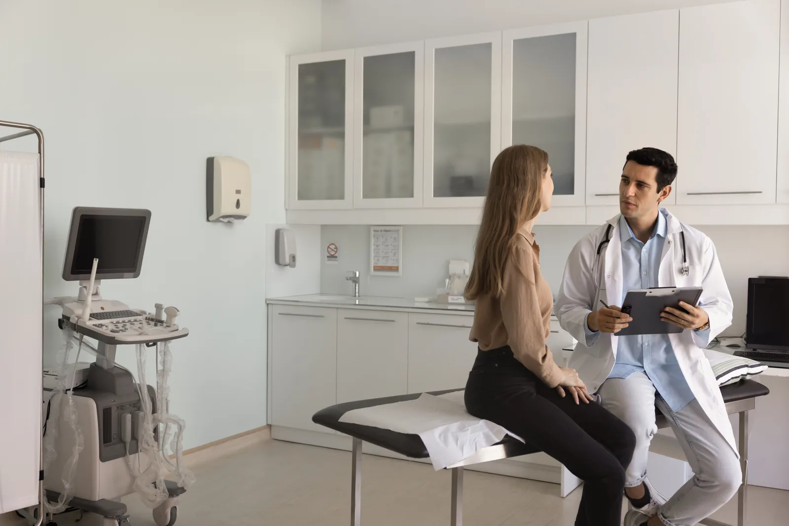 Urologist reviewing a scan with a seated patient during a consultation in a clinic exam room