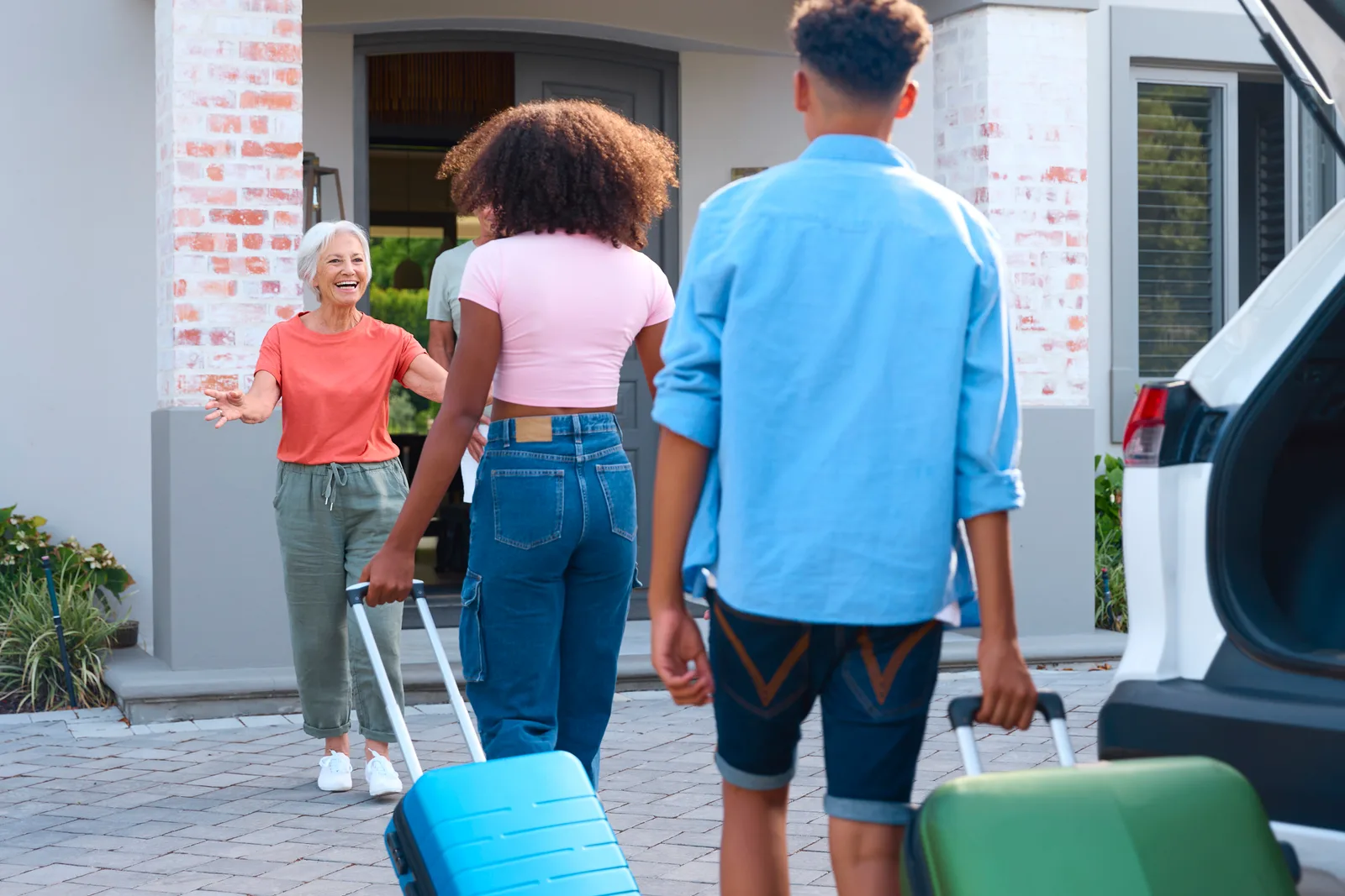 Vacation rental manager welcoming a family with luggage at the front door of a coastal rental home