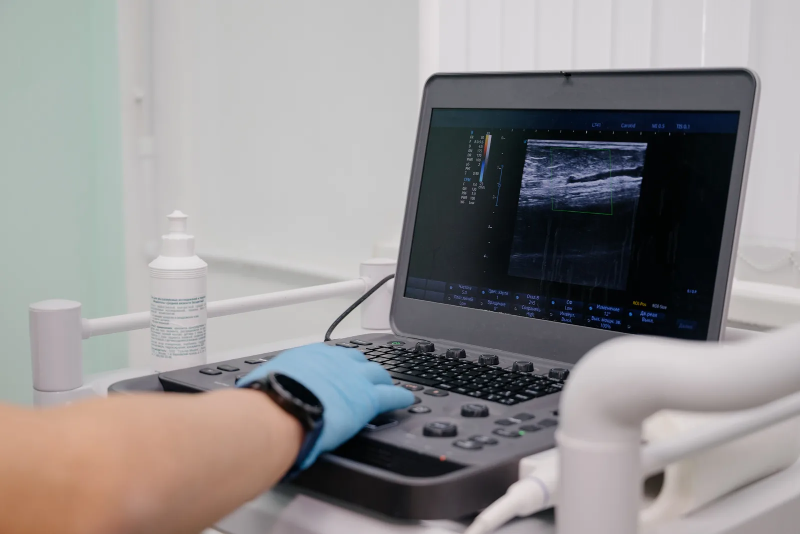 Vascular specialist using ultrasound to examine a patient's varicose veins in a clinic exam room
