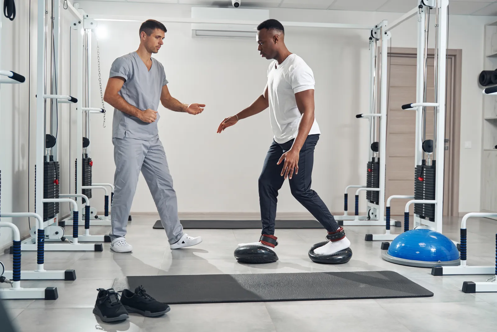 Physical therapist guiding a patient through a balance exercise on a foam pad during a vestibular therapy session